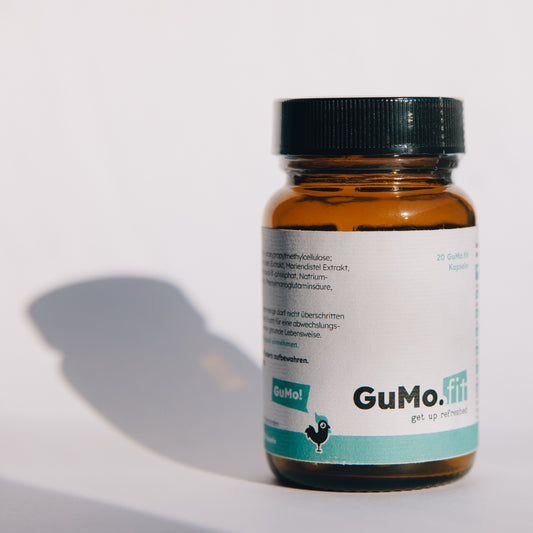 Braune GuMo.fit-Nahrungsergänzungsmittelflasche auf hellem Hintergrund, mit gut sichtbarem Etikett und Schattenwurf.